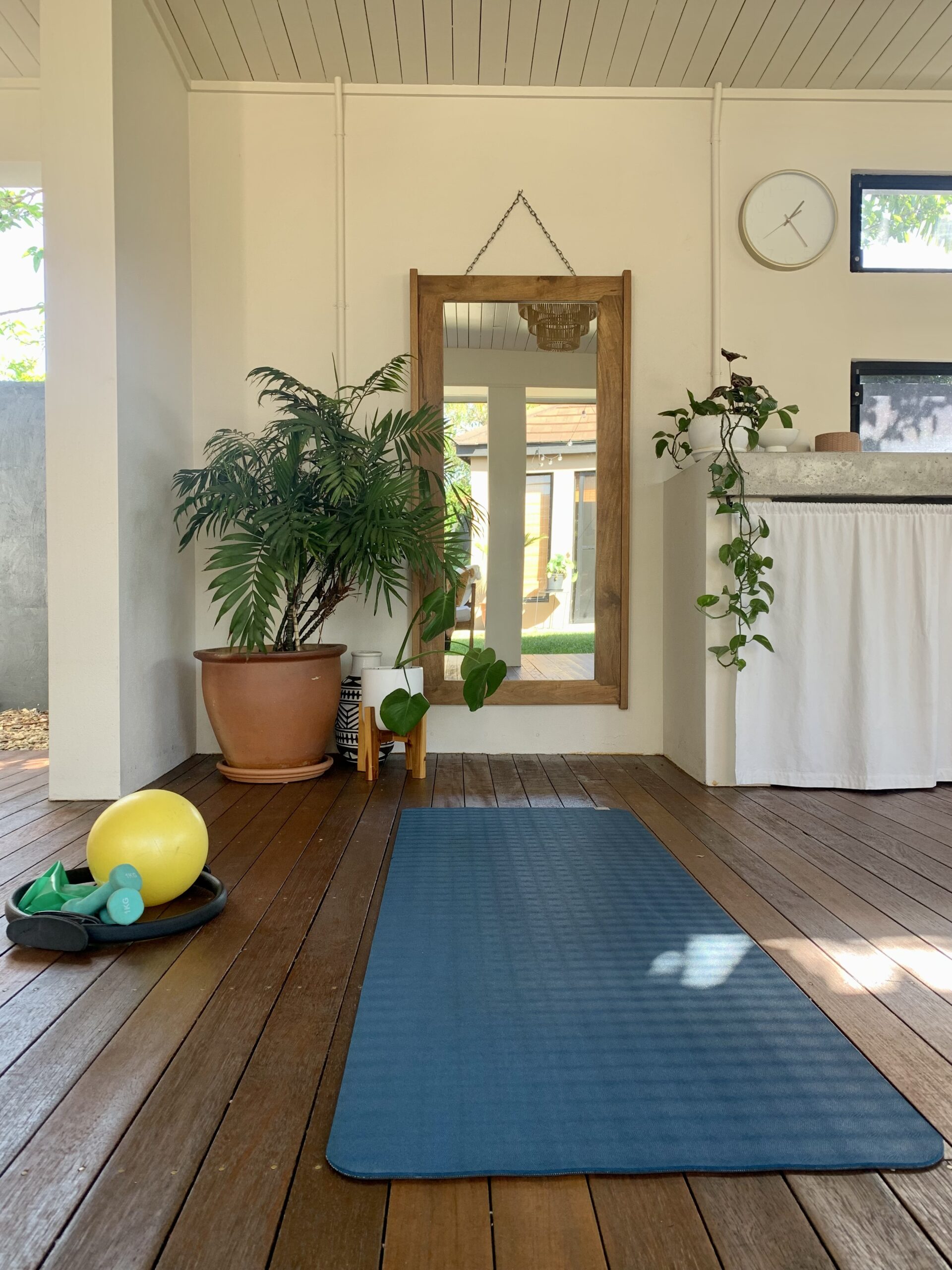 A Pilates mat, exercise ball and tropical plants on the Halo Pilates deck